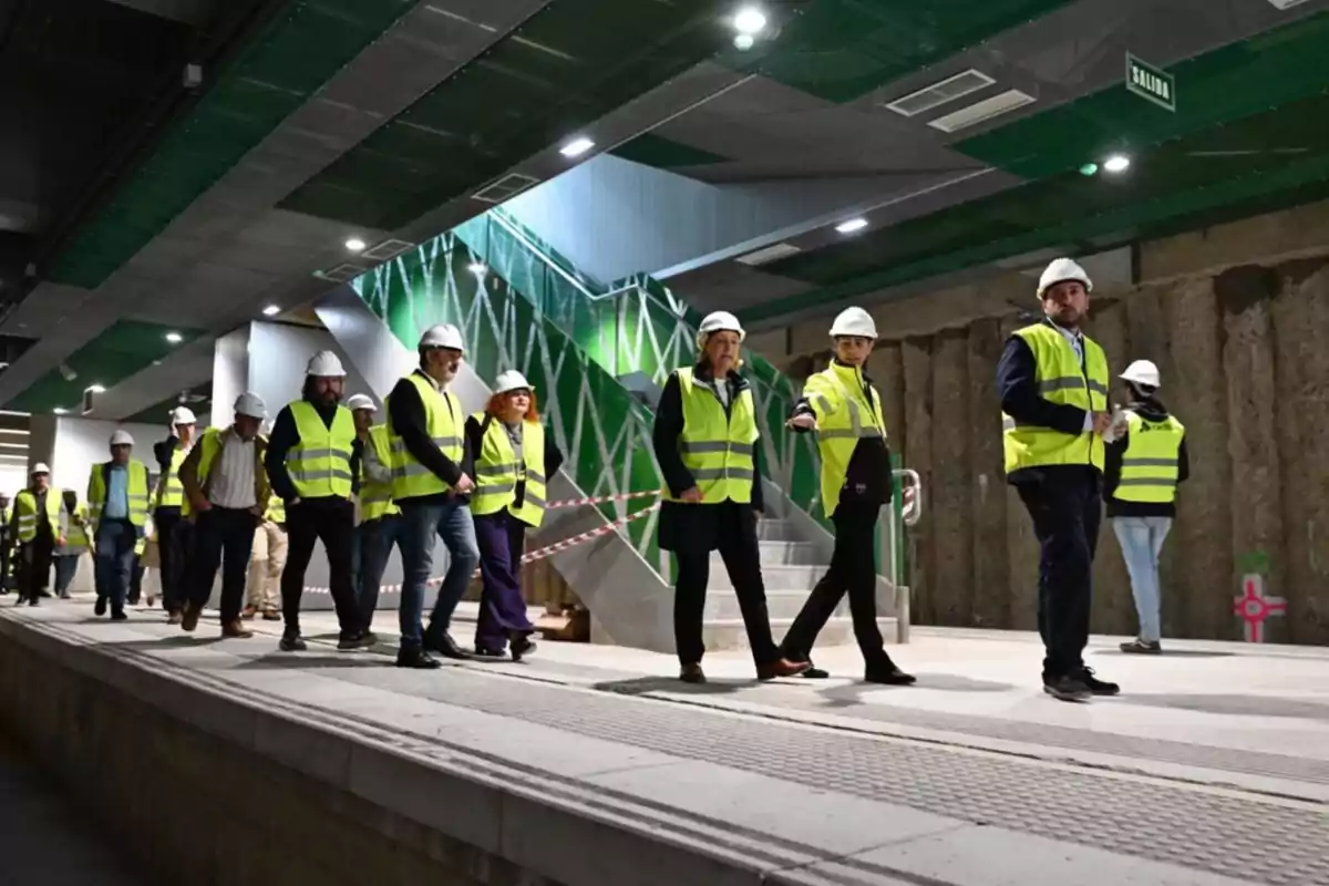 Personas con chalecos reflectantes y cascos recorriendo una construcción subterránea.