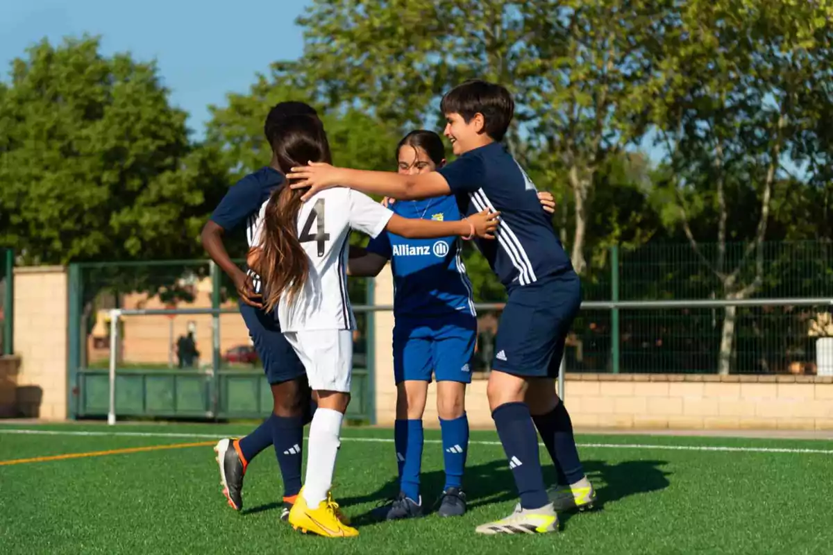 Niños jugando fútbol se abrazan en el campo celebrando un gol