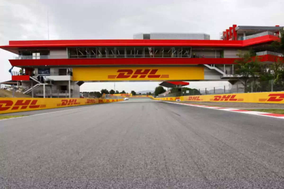 Vista de una pista de carreras con un puente de control y publicidad de DHL.