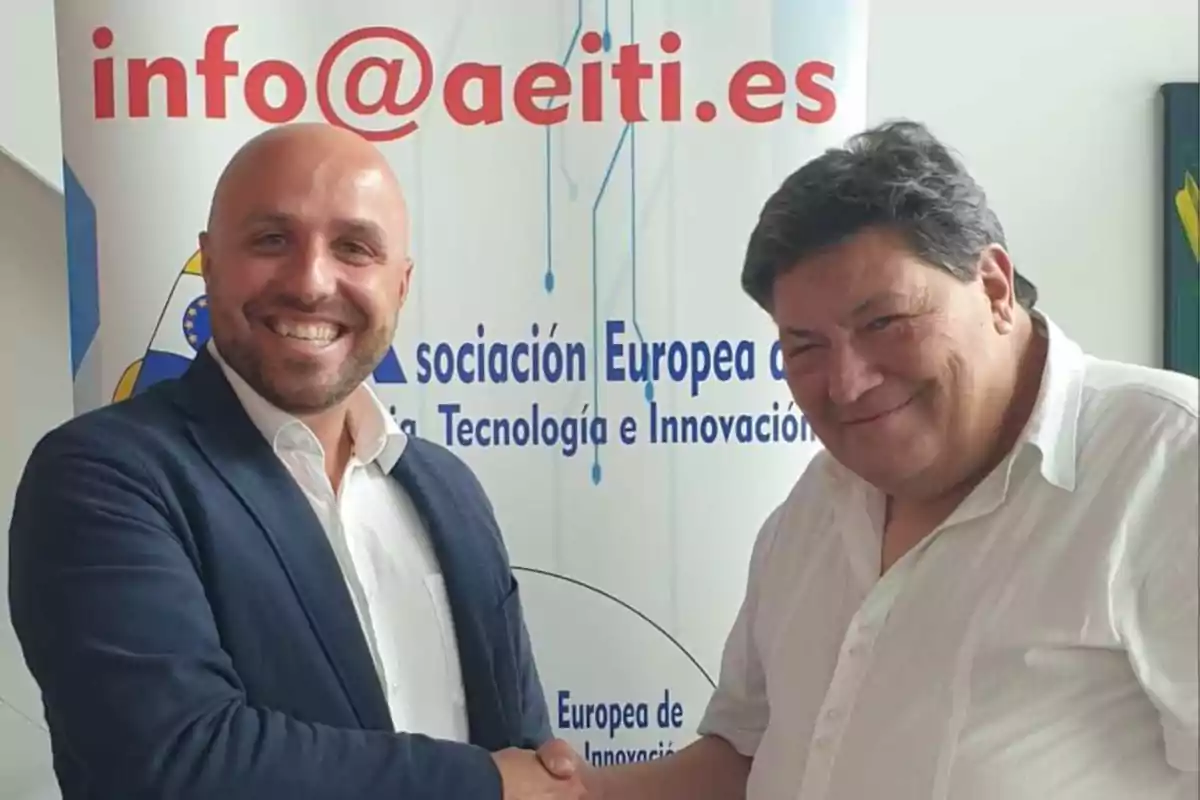 Dos hombres sonrientes se dan la mano frente a un cartel de la Asociación Europea de Tecnología e Innovación.