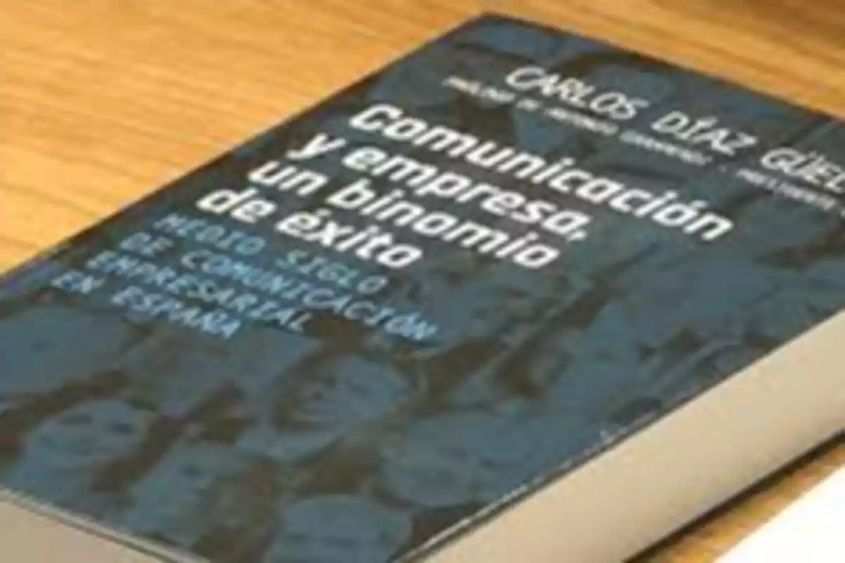 Libro titulado "Comunicación y empresa, un binomio de éxito" de Carlos Díaz Güell sobre una mesa de madera.