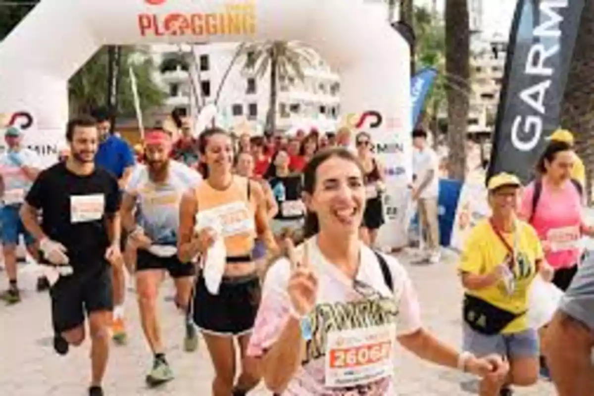 Grupo de personas participando en un evento de plogging al aire libre, con una mujer al frente haciendo el signo de la paz.