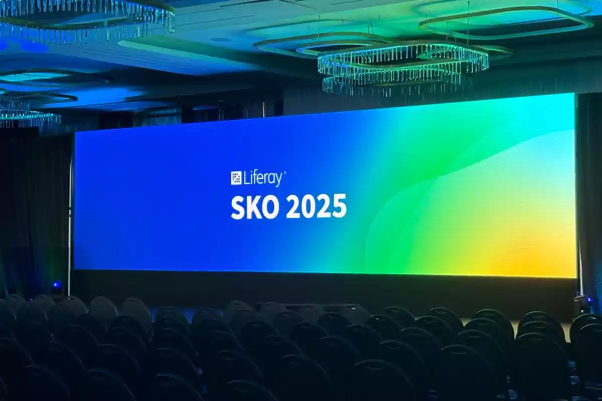 Pantalla grande en un auditorio mostrando "Liferay SKO 2025" con un fondo de colores azul y verde.