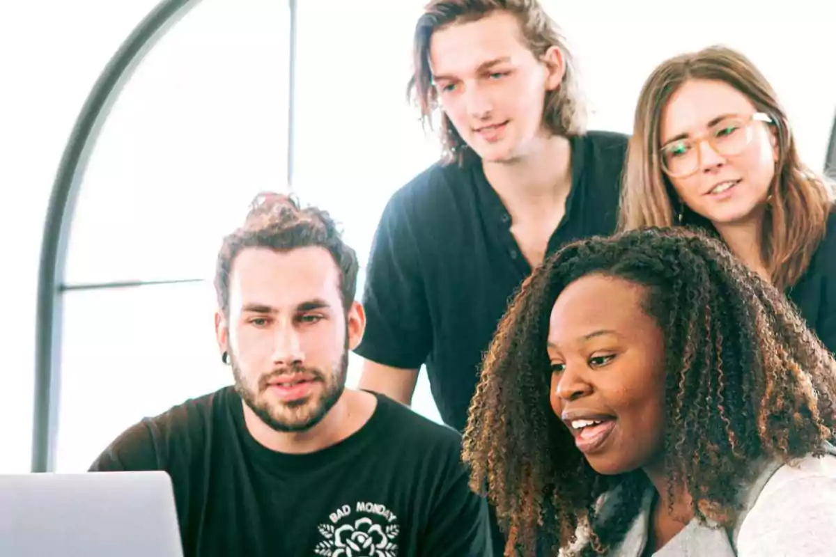 Un grupo de personas trabajando juntas en una computadora portátil.