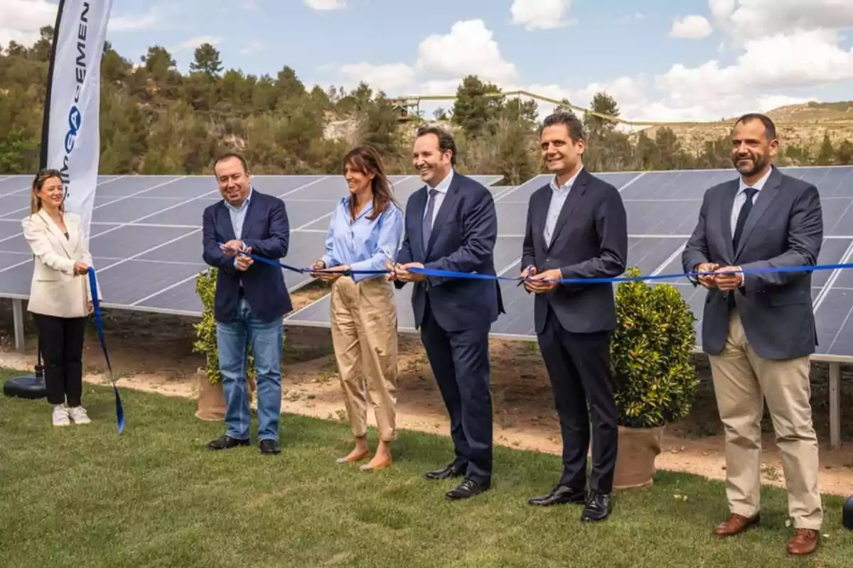 Personas cortando una cinta azul en una ceremonia de inauguración frente a paneles solares.