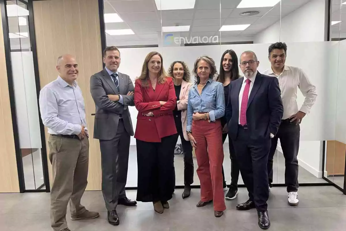 Un grupo de personas posando en una oficina moderna con paredes de vidrio y un letrero que dice "Envalora".