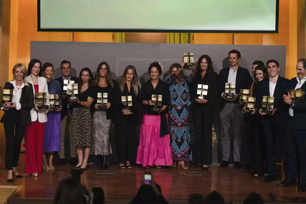 Un grupo de personas posando con trofeos en un evento de premiación.