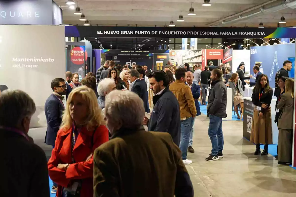 Personas interactuando en una feria de franquicias con varios stands y un ambiente profesional.