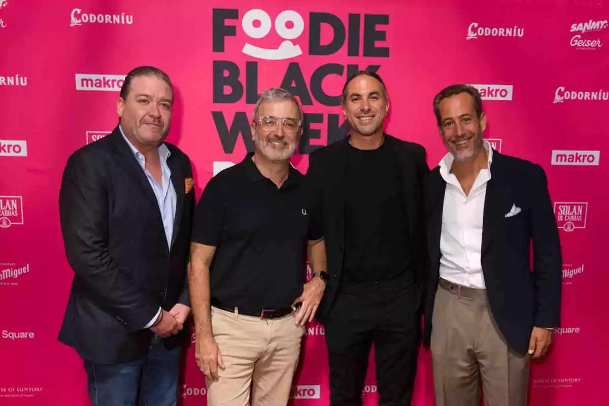 Cuatro hombres posan juntos frente a un fondo rosa con el texto "Foodie Black Week" y varios logotipos de marcas.