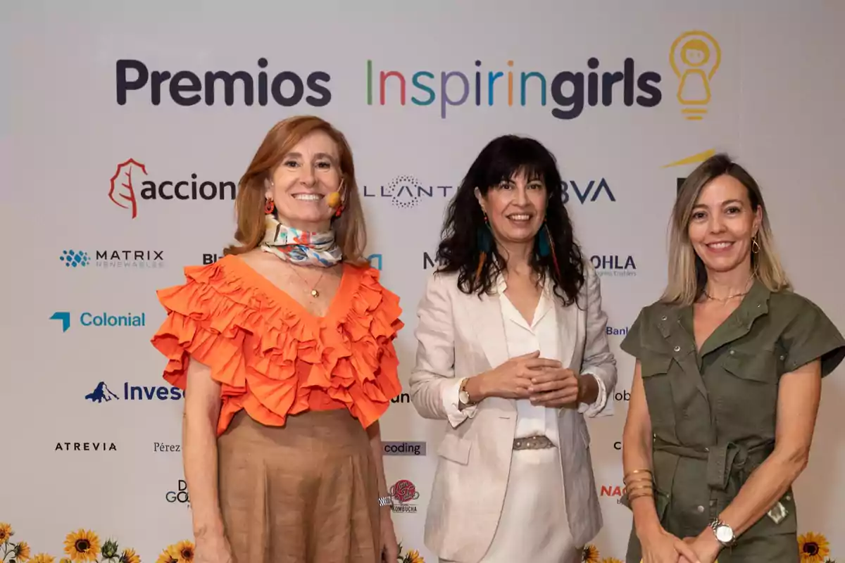 Tres mujeres sonríen frente a un fondo con logotipos de empresas y el texto Premios Inspiring Girls