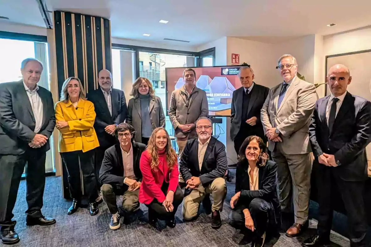 Un grupo de personas posando en una sala de conferencias con una pantalla de presentación al fondo.