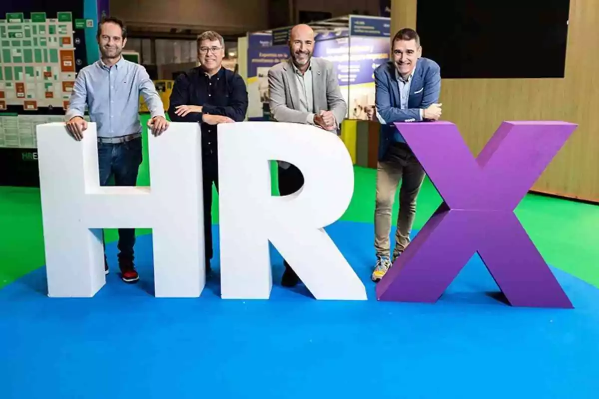 Cuatro personas posan detrás de grandes letras que forman "HRX" en un entorno de exposición.