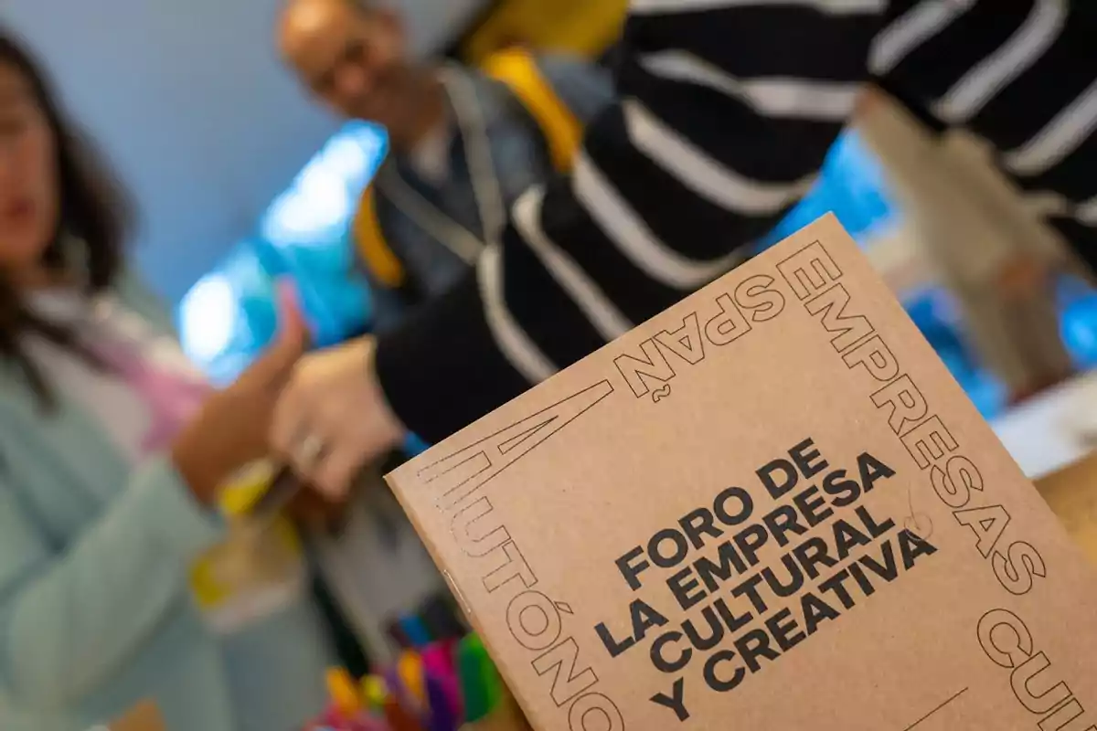 Personas interactuando en un evento con un cartel que dice "Foro de la Empresa Cultural y Creativa".