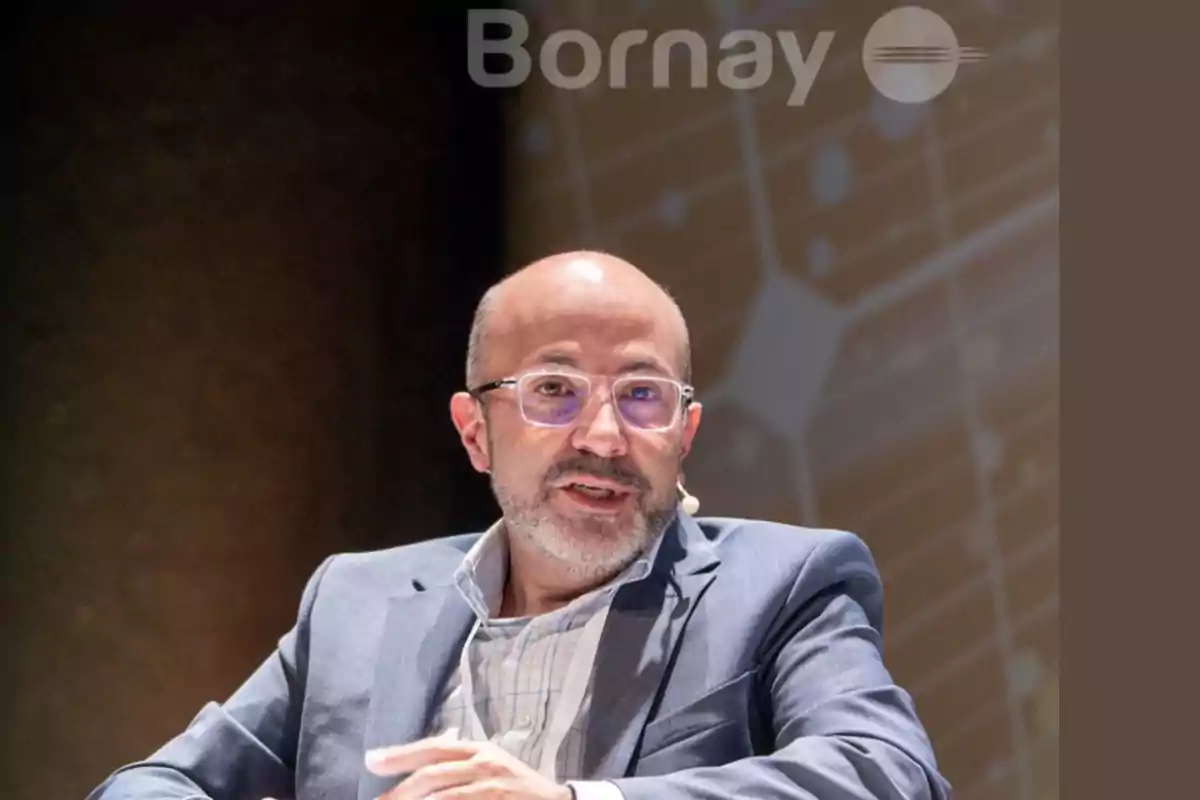 Un hombre con gafas y barba hablando en un evento con un fondo que muestra el logo de Bornay.