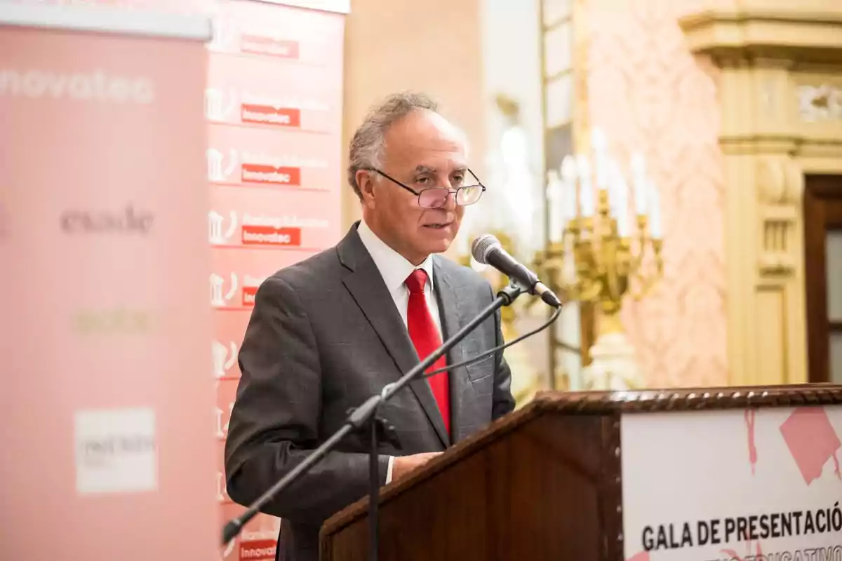 Un hombre con traje y corbata roja habla en un podio durante un evento de presentación de Innovatec.