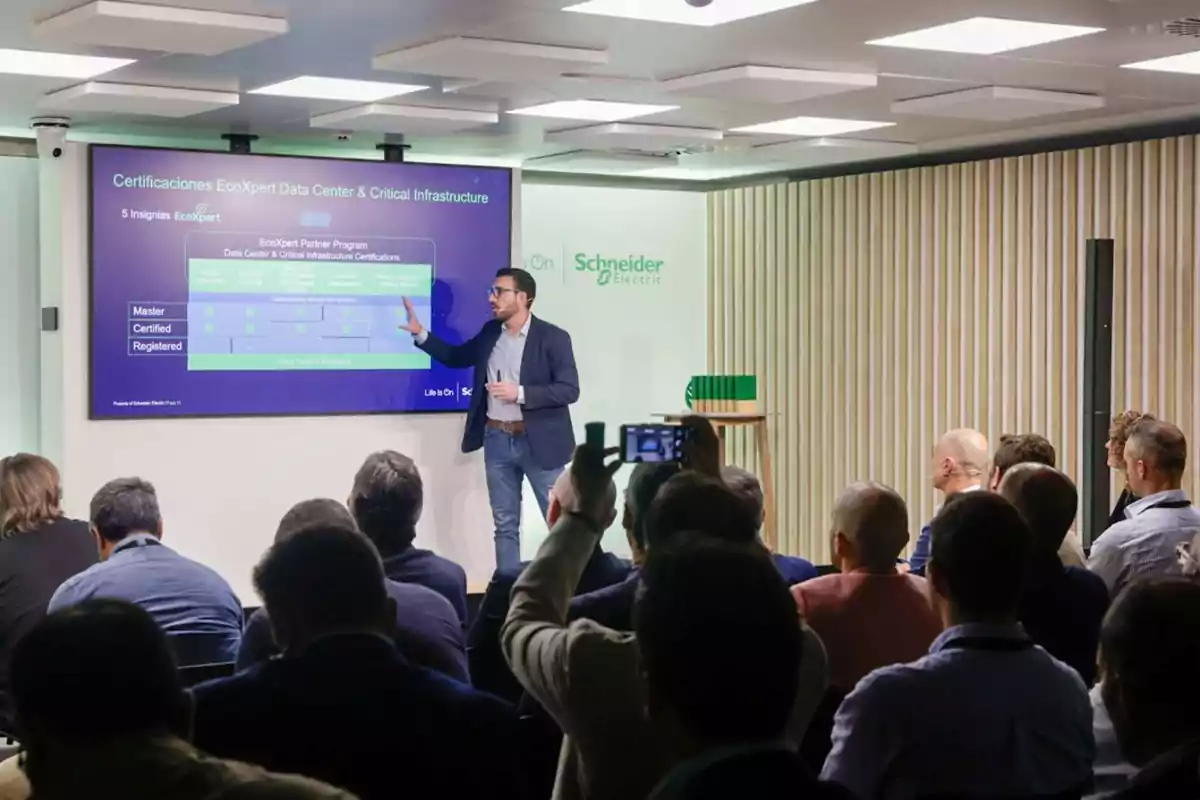 Un hombre da una presentación sobre certificaciones de infraestructura crítica y centros de datos EcoXpert de Schneider Electric frente a una audiencia.