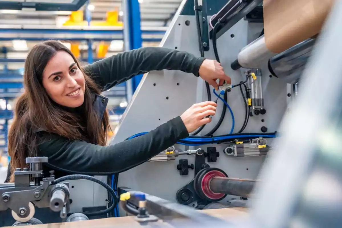 Mujer trabajando en una máquina industrial en un entorno de fábrica.