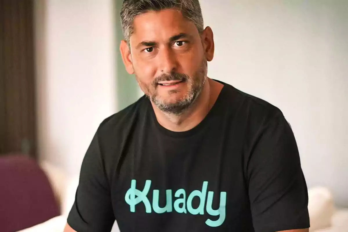 Hombre con barba y cabello corto, usando una camiseta negra con el logo de "Kuady" en letras verdes.