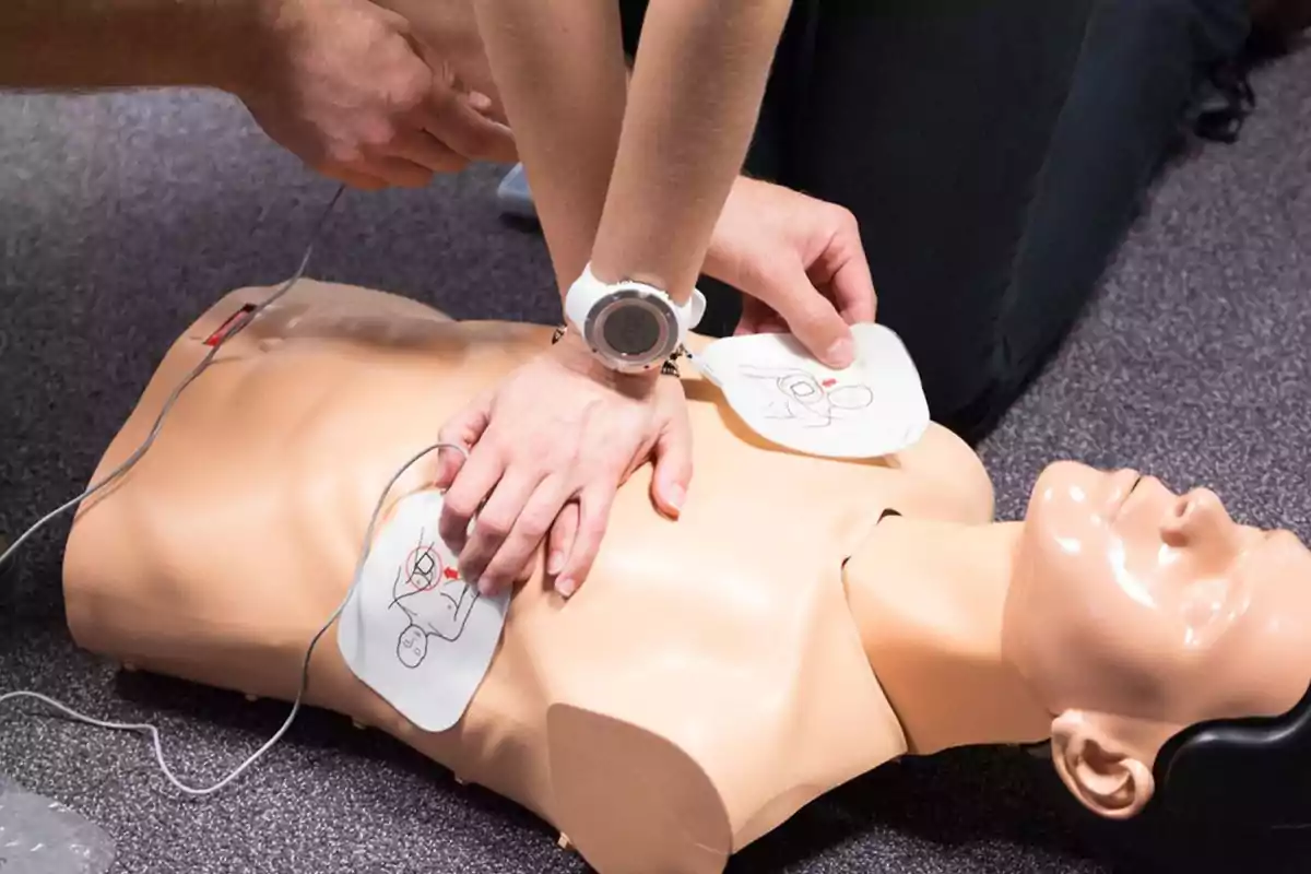 Persona realizando maniobras de reanimación cardiopulmonar (RCP) en un maniquí de entrenamiento.