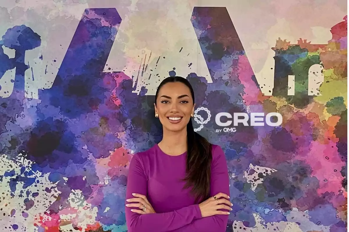 Mujer sonriendo con los brazos cruzados frente a un fondo colorido con el logo de CREO by OMG.