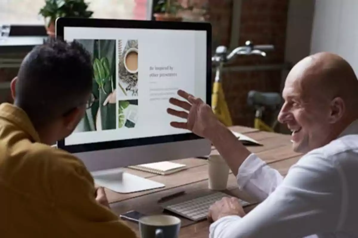 Dos personas trabajando juntas en una computadora, una de ellas señalando la pantalla y la otra observando atentamente.