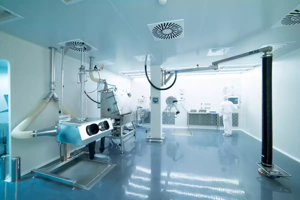 Laboratorio limpio y moderno con equipos de alta tecnología y una persona usando traje de protección trabajando en el fondo