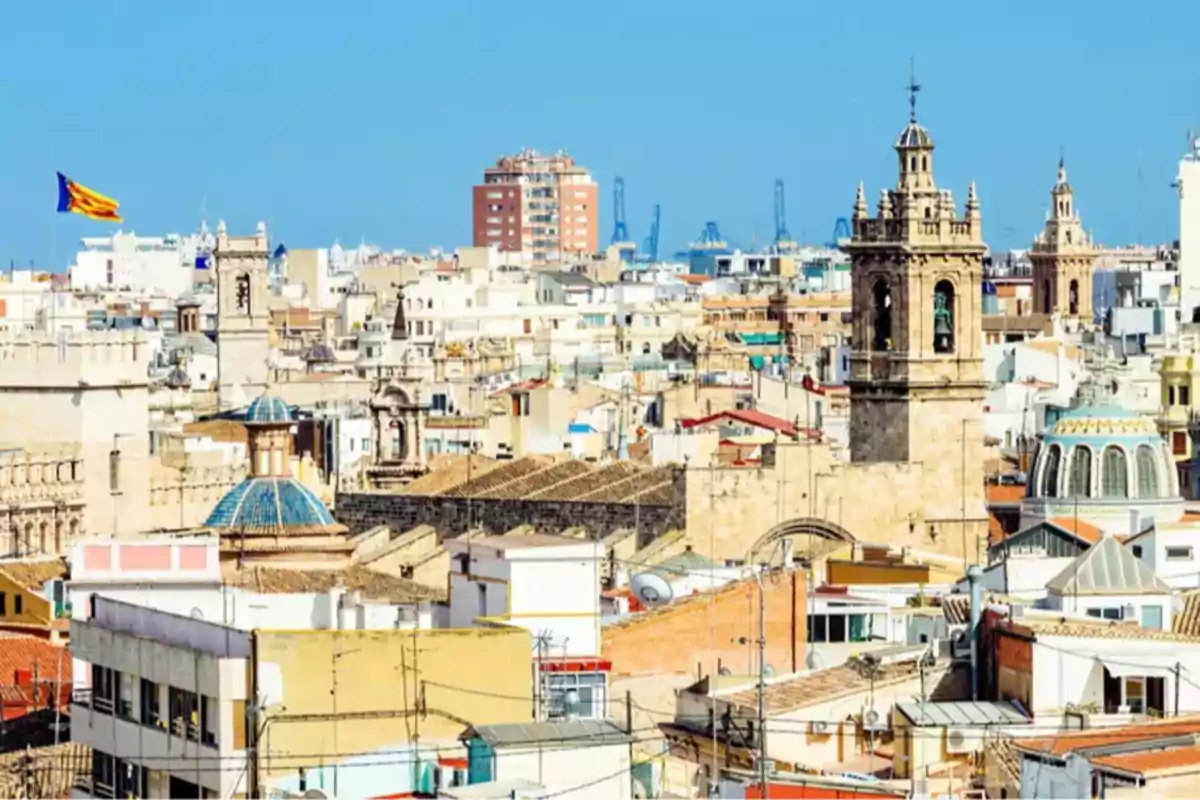 Vista panorámica de una ciudad con edificios históricos y una bandera ondeando en el cielo azul.