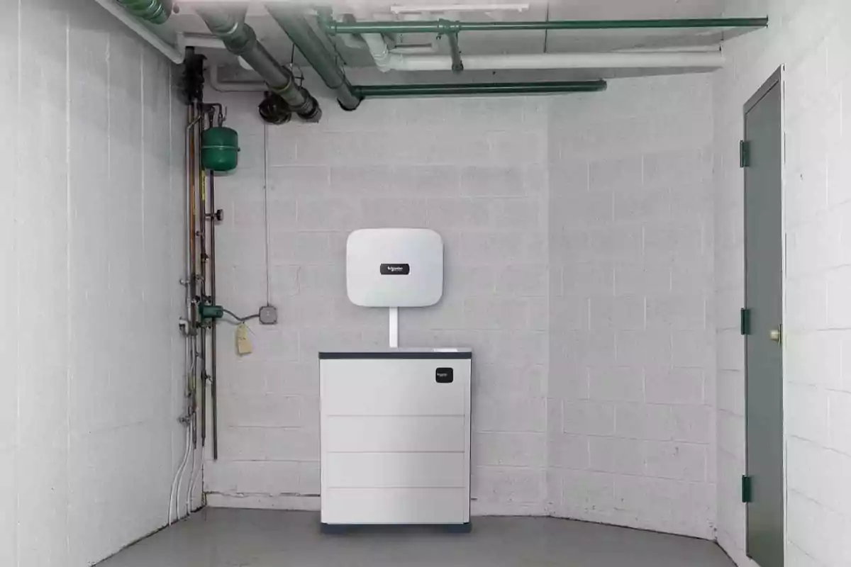 Un dispositivo de almacenamiento de energía instalado en una habitación con paredes de bloques de concreto y tuberías verdes en el techo.