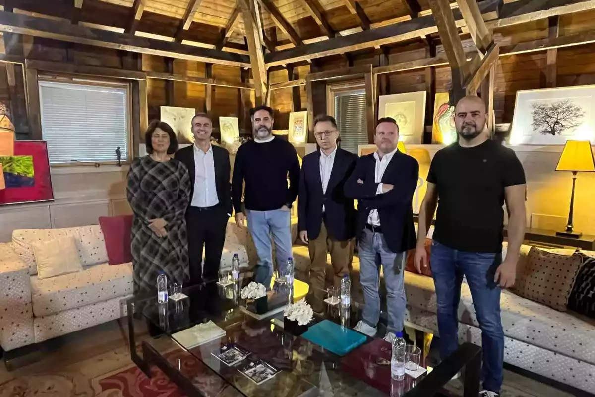 Un grupo de seis personas posando en una sala con techo de madera y obras de arte en las paredes.