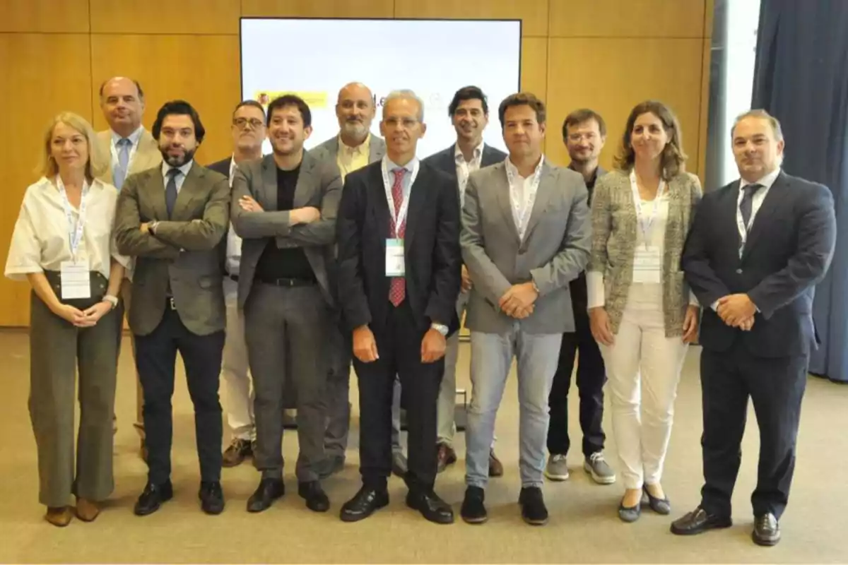 Un grupo de personas posando juntas en un entorno profesional con fondo de madera y una pantalla.