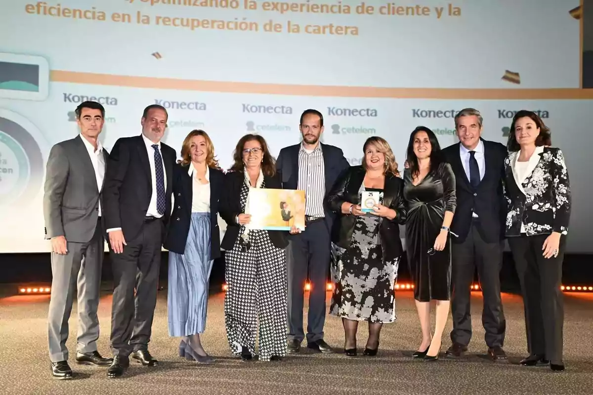 Un grupo de personas posando juntas en un evento corporativo con un fondo que muestra logotipos y texto relacionado con la experiencia del cliente y la eficiencia.