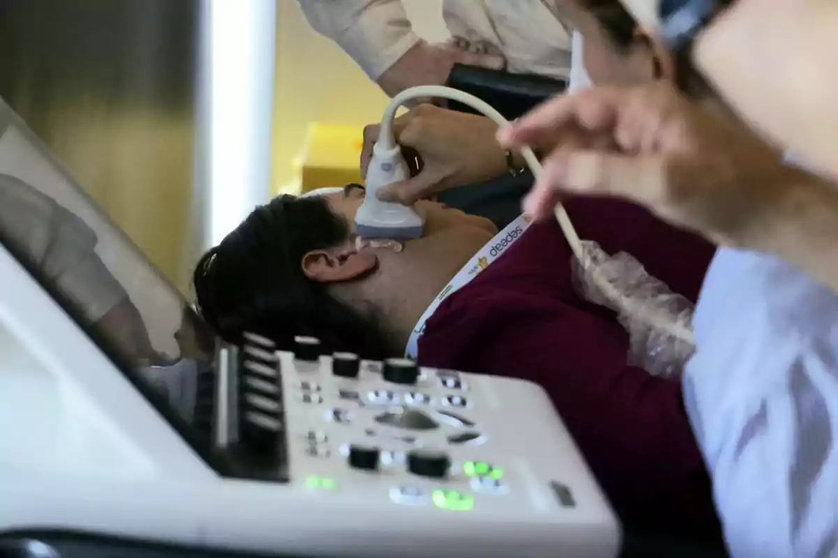 Persona recibiendo un ultrasonido en el cuello mientras está acostada en una camilla médica.