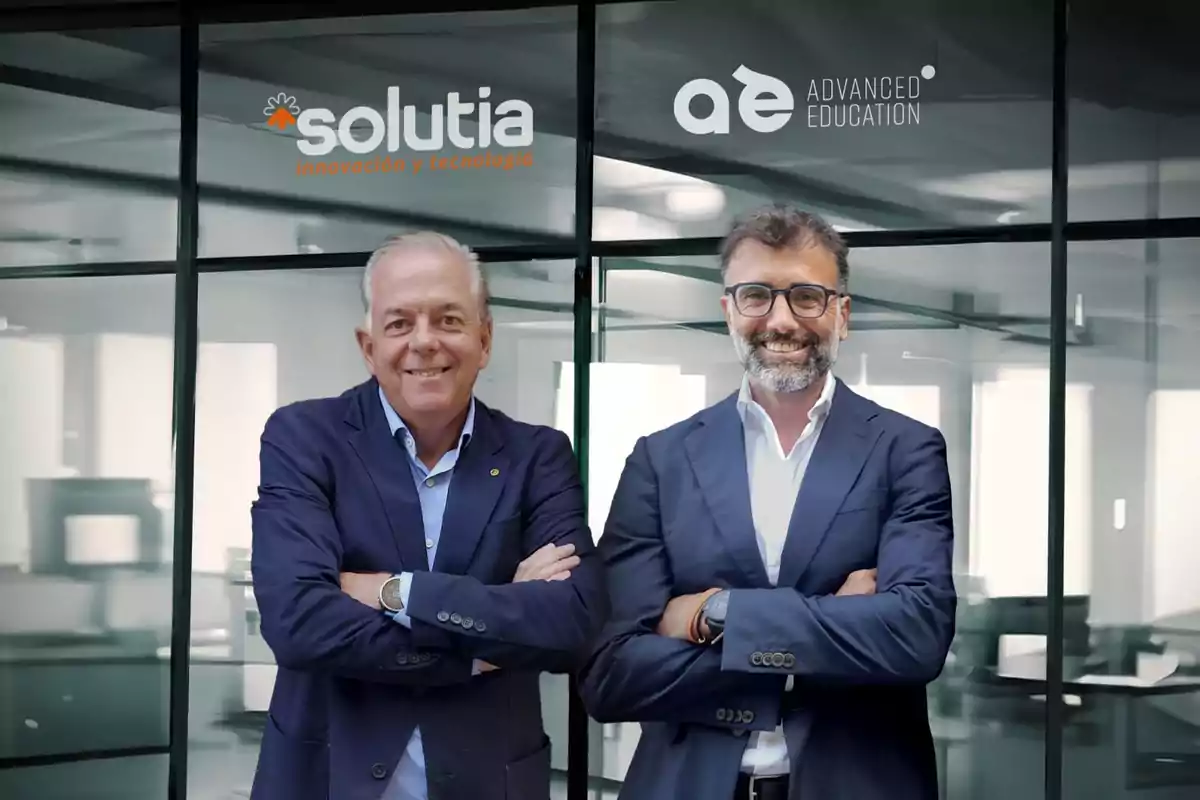 Dos hombres de traje sonríen con los brazos cruzados frente a una pared de vidrio con los logotipos de Solutia y Advanced Education.