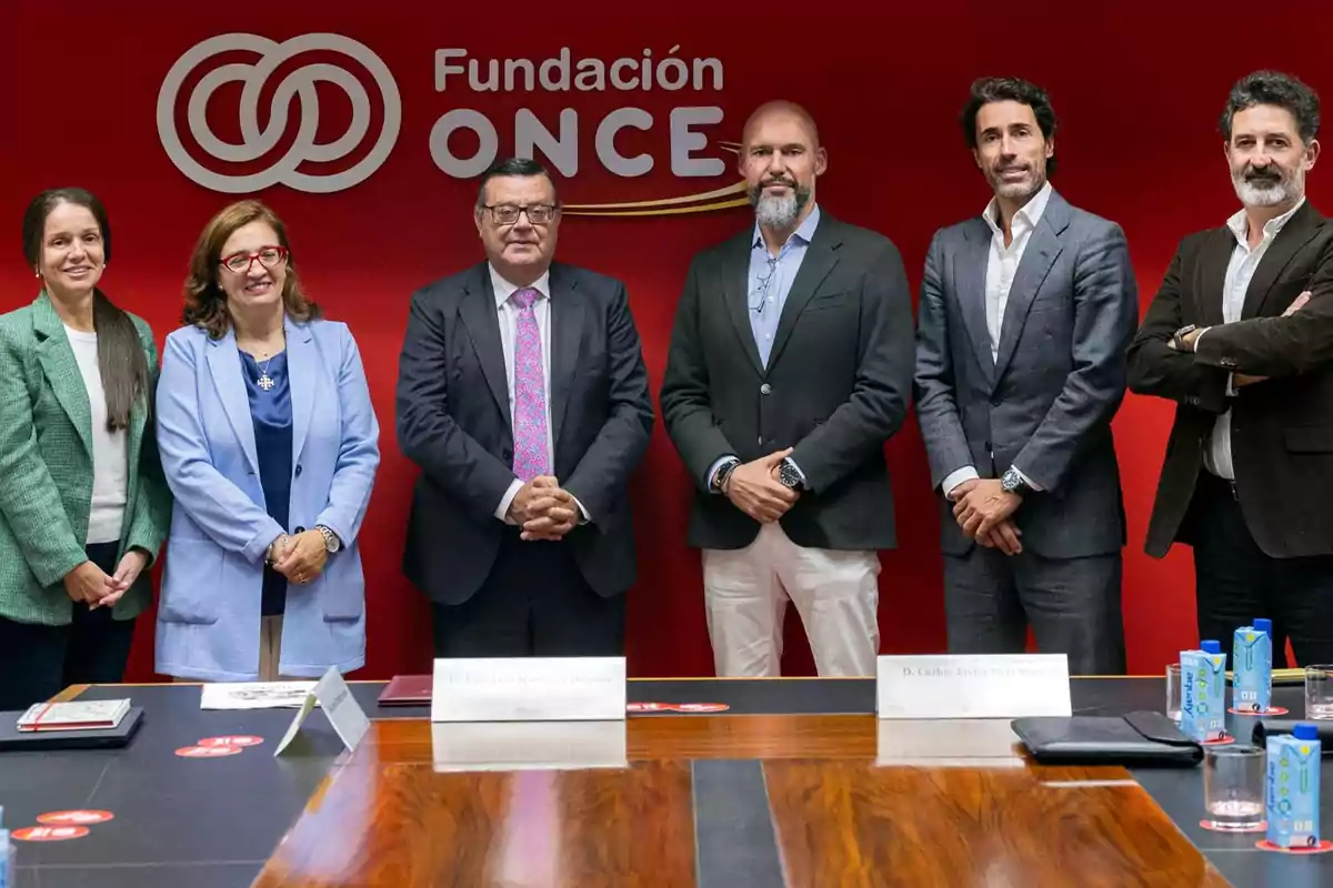 Un grupo de personas posando frente a un fondo rojo con el logo de la Fundación ONCE.