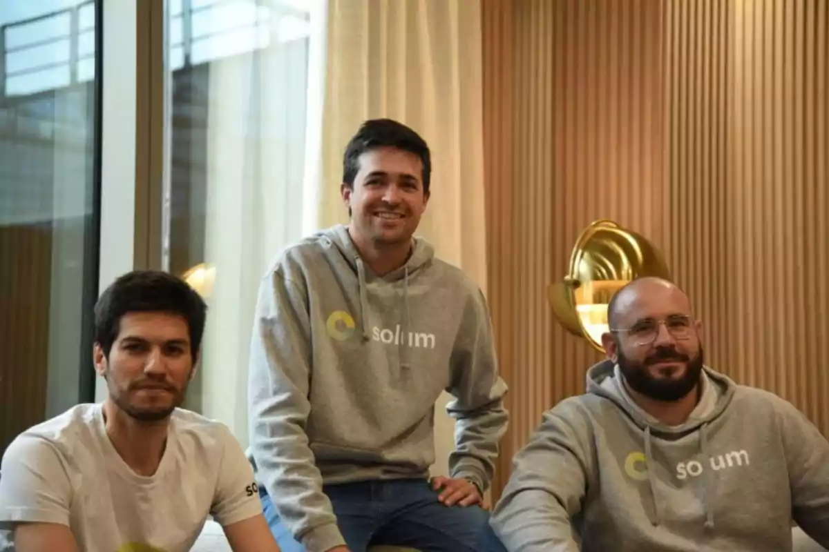 Tres personas posan en un ambiente interior con sudaderas y camisetas de la marca Solum.