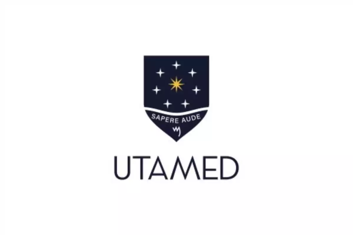 Escudo azul con una estrella dorada rodeada de estrellas blancas y el lema "SAPERE AUDE" encima del texto "UTAMED".