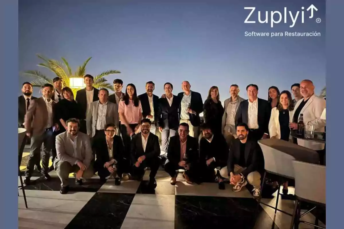 Grupo de personas posando en un evento al aire libre al atardecer con palmeras de fondo y el logo de Zupliy en la esquina superior derecha